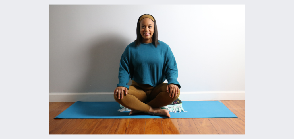 yoga teacher sitting on a yoga bolster and blanket