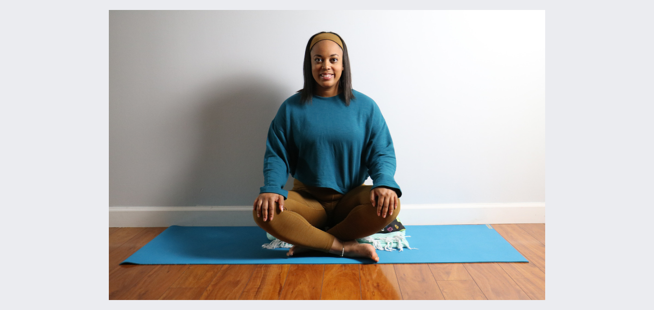 yoga teacher sitting on a bolster and blanket